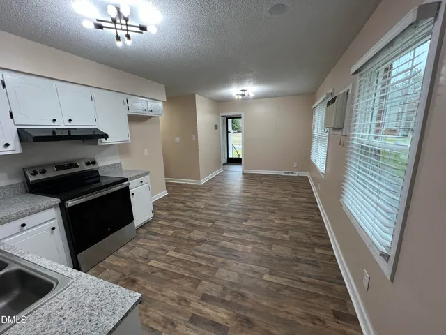 a kitchen with granite countertop a stove a sink and a refrigerator