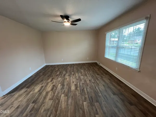 a view of empty room with wooden floor and fan