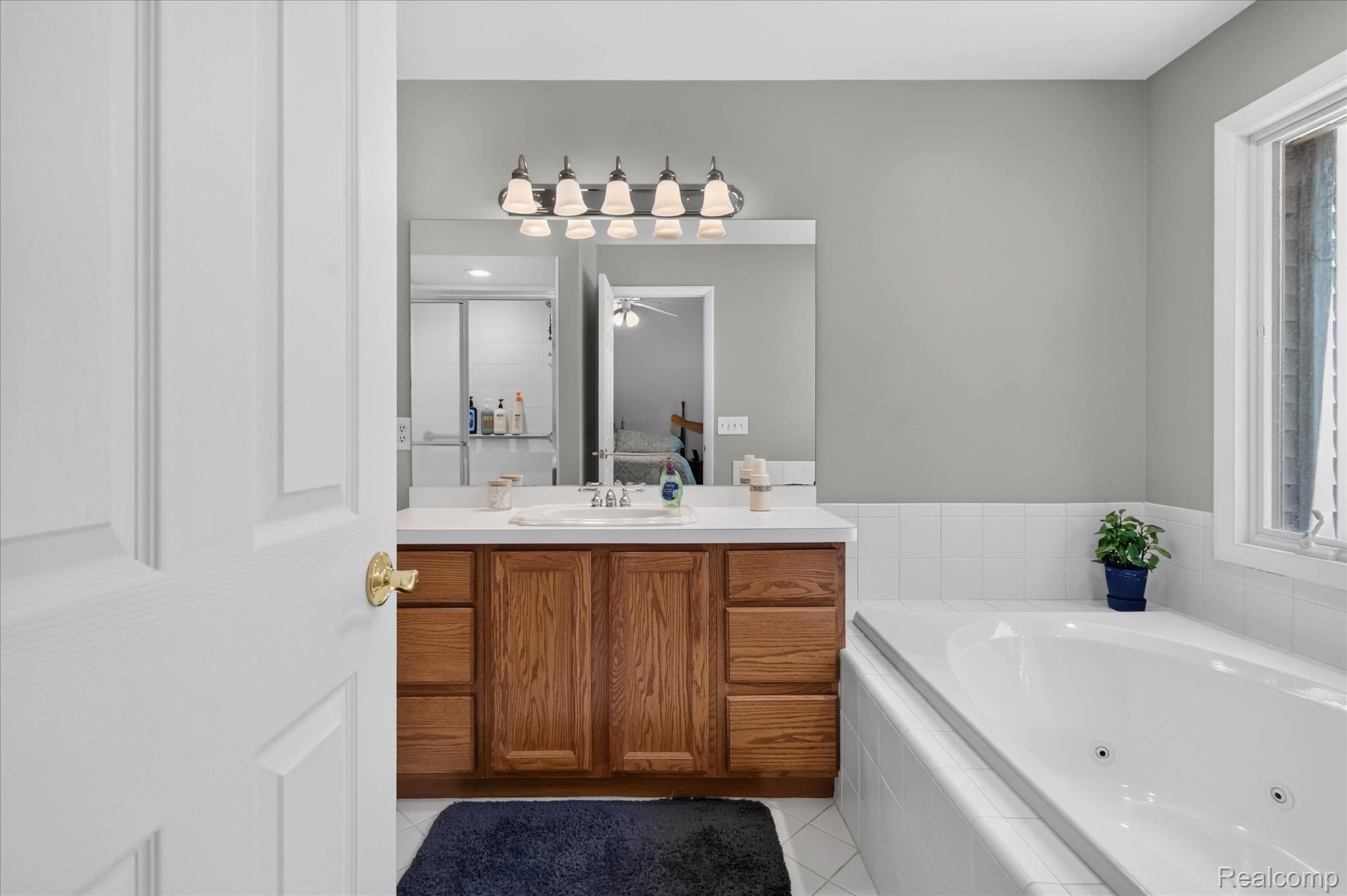 4037 Chilson Road Howell, MI 48843 - Photo 31 of 69 Bathroom featuring a built-in tub, wood-finish vanity, integrated sink, and overhead lighting fixture
