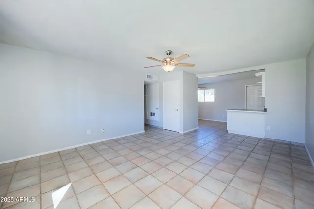 a view of an empty room with a chandelier fan