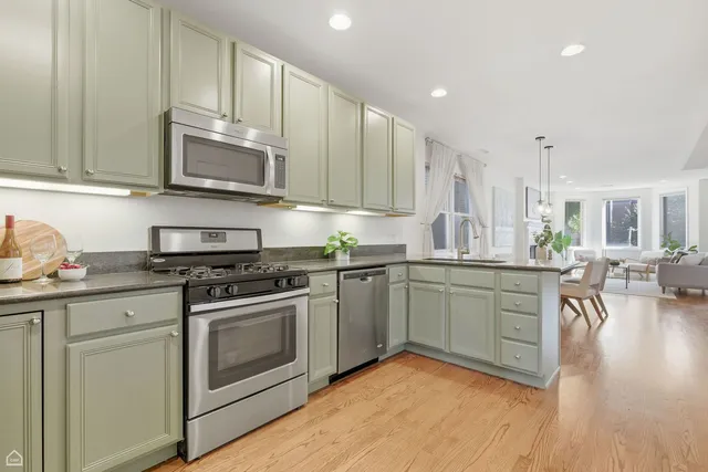 a kitchen with stainless steel appliances granite countertop a stove top oven a sink dishwasher and white cabinets with wooden floor