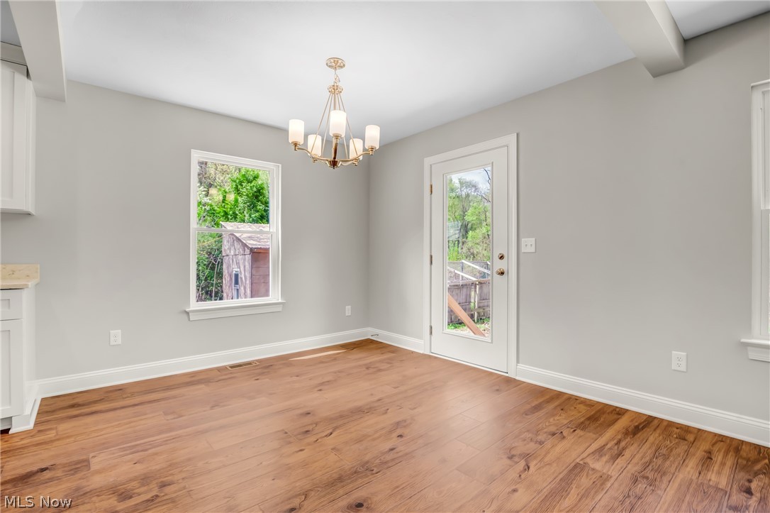 12412 Snow Road Burton, OH 44021 - Photo 10 of 45 Empty room featuring beamed ceiling, light hardwood / wood-style flooring, and an inviting chandelier