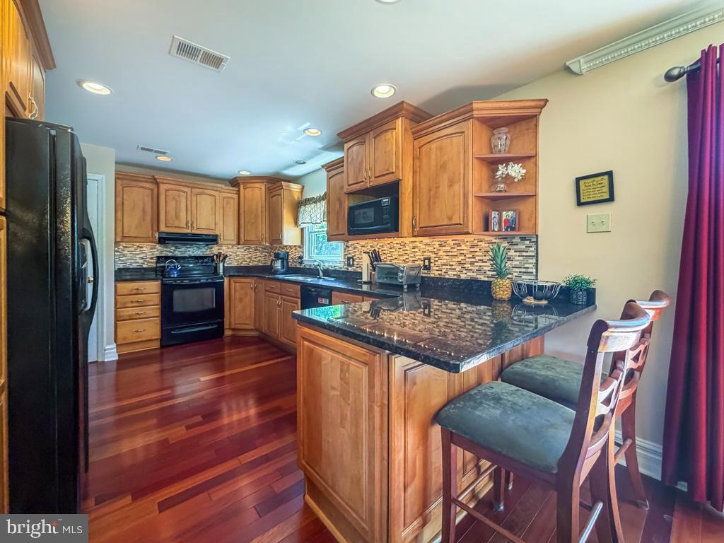 925 Big Oak Road Yardley, PA 19067 - Photo 20 of 51 a kitchen with stainless steel appliances granite countertop a stove top oven a refrigerator a sink and dishwasher with wooden floor