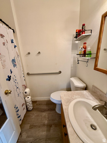 1353 360 West Payson, UT 84651 - Photo 9 of 16 Bathroom featuring wood-finish flooring, a light-toned countertop with an integrated sink, a wood-finish vanity, and a grab bar