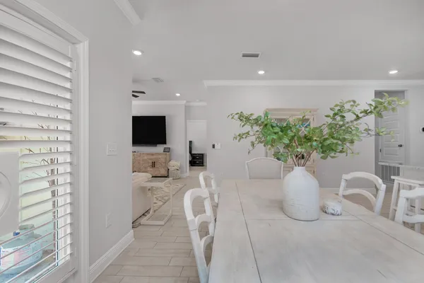 a white vase with flowers sitting on a table and chair