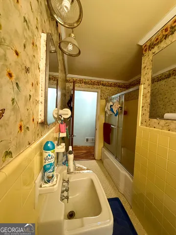 a bathroom with a sink and mirror with bathtub
