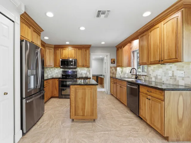 a kitchen with stainless steel appliances granite countertop a stove top oven a sink and a refrigerator