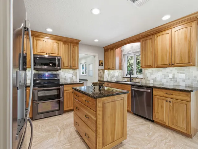a kitchen with stainless steel appliances granite countertop a sink and a refrigerator
