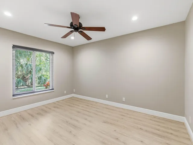 an empty room with wooden floor and ceiling fan