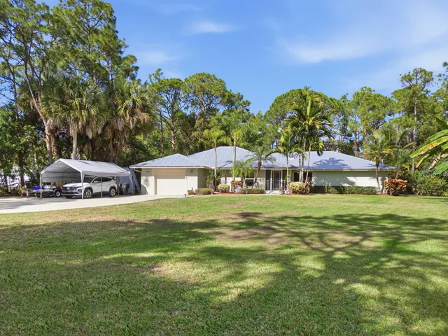 a front view of a house with a garden and trees