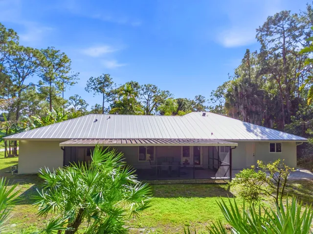 an aerial view of residential house with outdoor space and trees all around