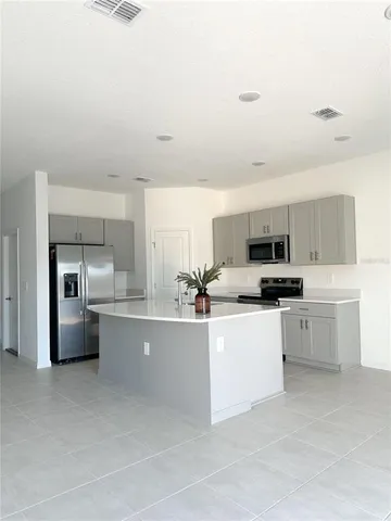 a kitchen with stainless steel appliances a sink a stove a refrigerator cabinets and a window