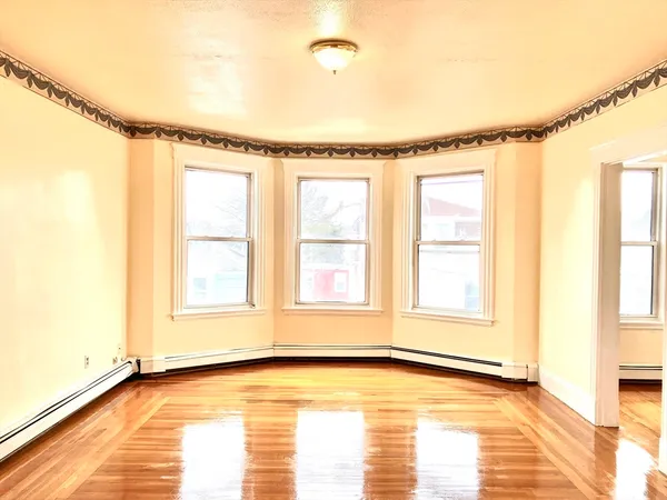 a view of an empty room with a window and wooden floor