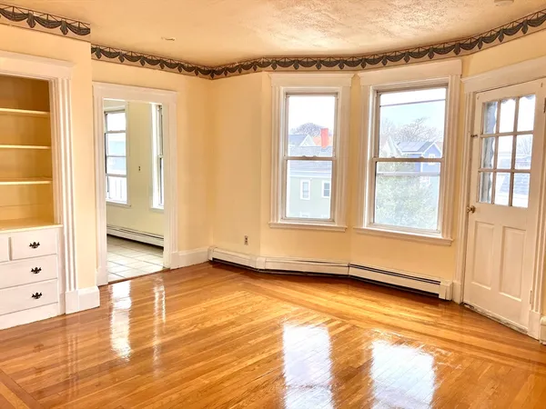 a view of an empty room with a window and wooden floor