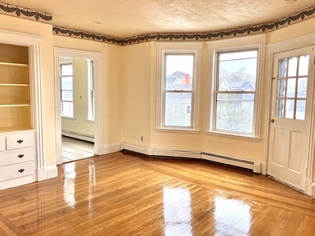 41 Brimblecom Street, Unit 3 Lynn, MA 01902 - Photo 5 of 16 a view of an empty room with a window and wooden floor