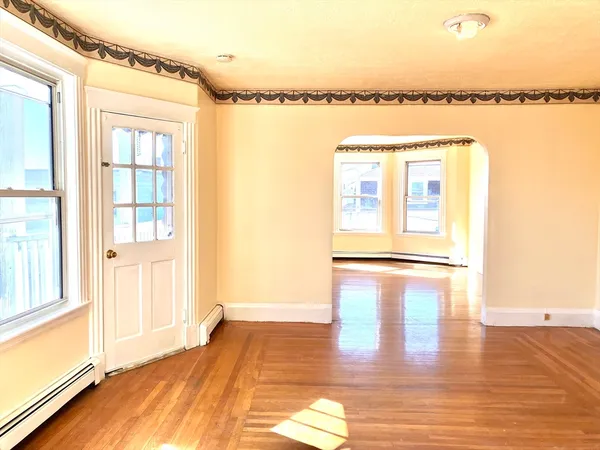 a view of a room with a large window and wooden floor
