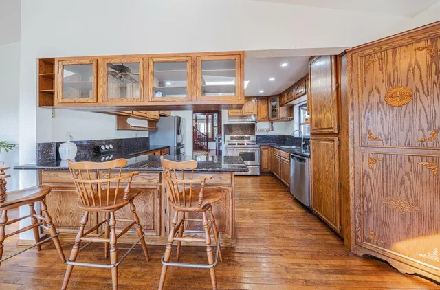 a kitchen with stainless steel appliances granite countertop a refrigerator and wooden cabinets