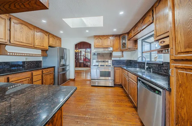 a large kitchen with stainless steel appliances wooden floor a stove and a refrigerator