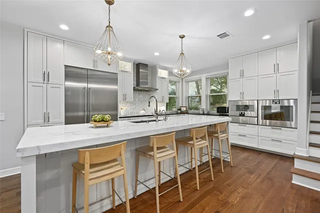 a kitchen with stainless steel appliances kitchen island granite countertop a table chairs and a refrigerator