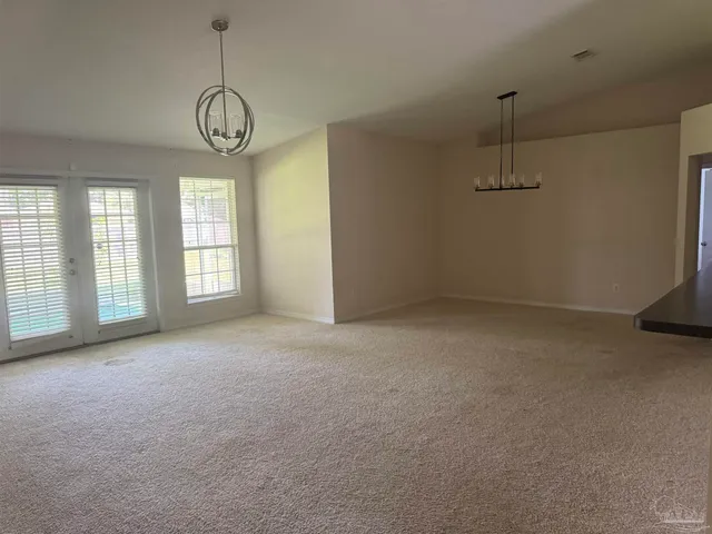a view of empty room with windows and chandelier