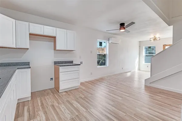 a view of empty room with wooden floor and kitchen