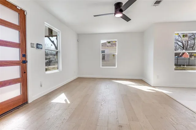 a view of an empty room with wooden floor and a window