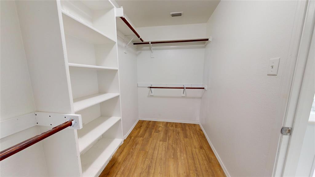 3101 Buckthorn Street Forney, TX 75126 - Photo 20 of 40 Walk-in closet featuring white built-in shelving, multiple hanging rods, and wood-finish flooring