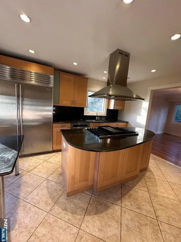 a large kitchen with stainless steel appliances kitchen island granite countertop a sink a counter space and cabinets