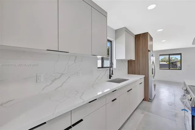 a large white kitchen with a sink and stainless steel appliances