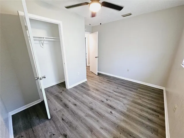 an empty room with wooden floor cabinet and a kitchen view