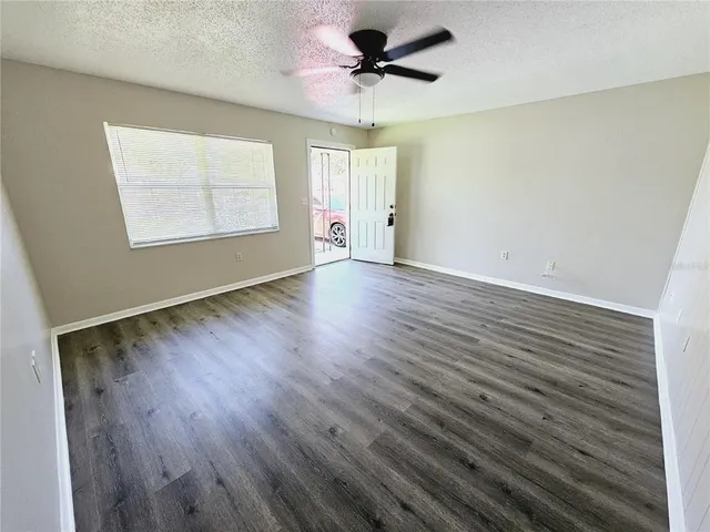 a view of an empty room with a window and wooden floor