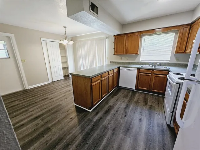 a kitchen with granite countertop wooden floors and white stainless steel appliances