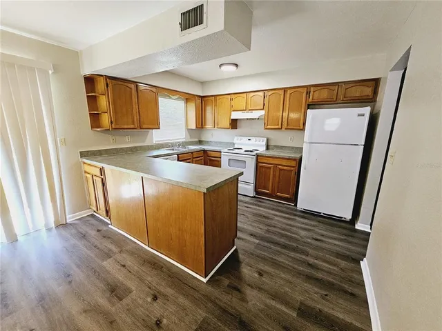 a kitchen with wooden floors and white cabinets