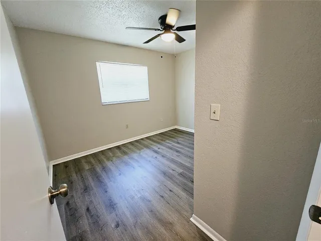 an empty room with a hardwood and a ceiling fan