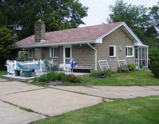 Exterior Front. Although the front of the house has a screened in porch--the owners always used the rear as the entrance to their house. The construction is a faced decorative block.  Rear deck is Trex and underneath the decking is the cistern for the well.