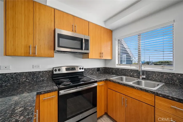 a kitchen with stainless steel appliances granite countertop a sink a stove a microwave and wooden cabinets