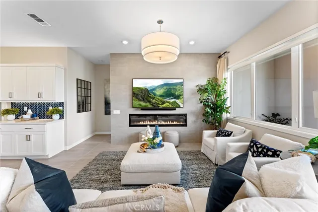 a living room with white couches and a dining table with kitchen view