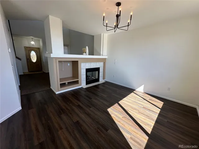 an empty room with wooden floor fireplace and windows