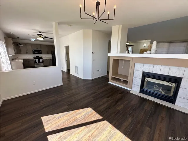 a living room with stainless steel appliances wooden floor and a fireplace
