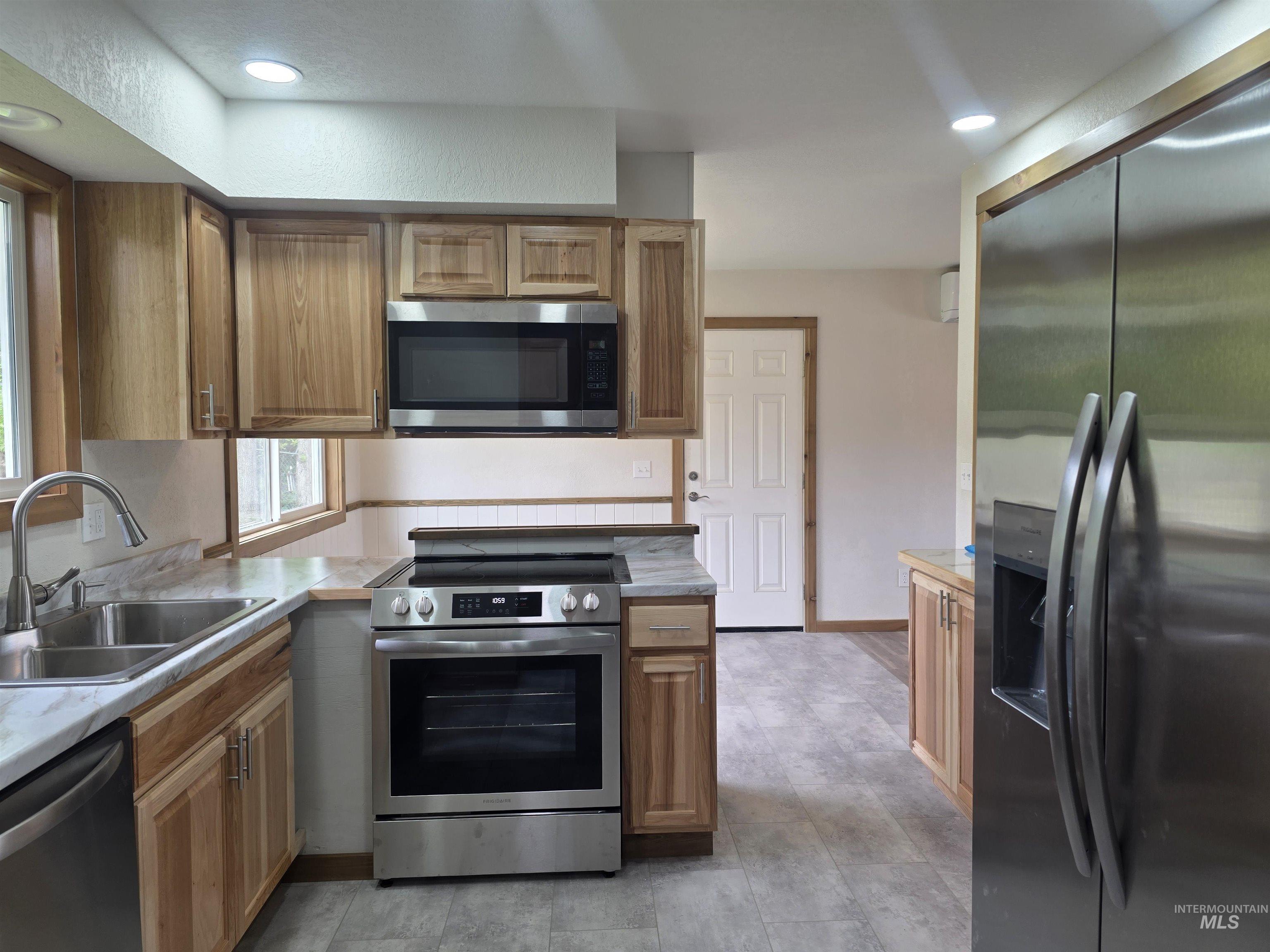 310 Fir Road Kamiah, ID 83536 - Photo 13 of 32 Kitchen featuring wood cabinetry, stainless steel appliances, a dual basin sink, light-toned countertops, and recessed lighting