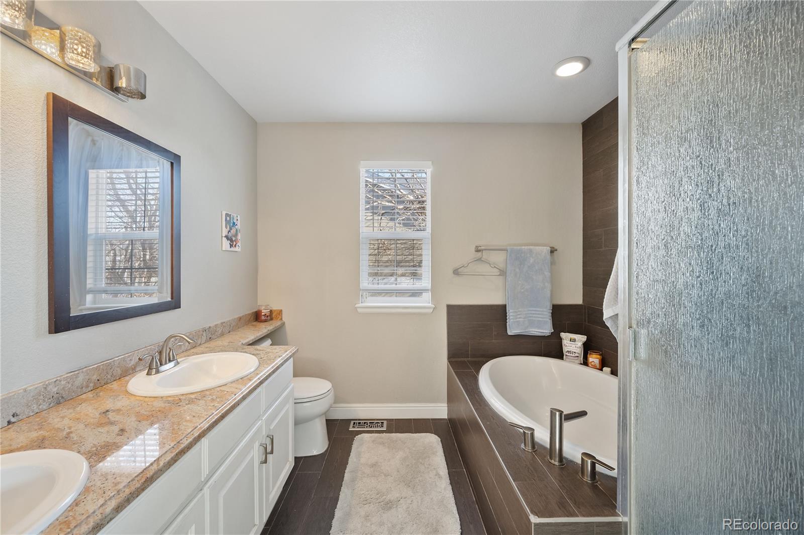 1201 Riddlewood Road Highlands Ranch, CO 80129 - Photo 22 of 36 a bathroom with a granite countertop sink a mirror a toilet and a shower