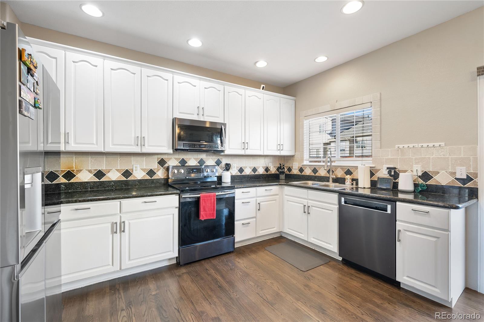 1201 Riddlewood Road Highlands Ranch, CO 80129 - Photo 10 of 36 a kitchen with granite countertop white cabinets and white appliances
