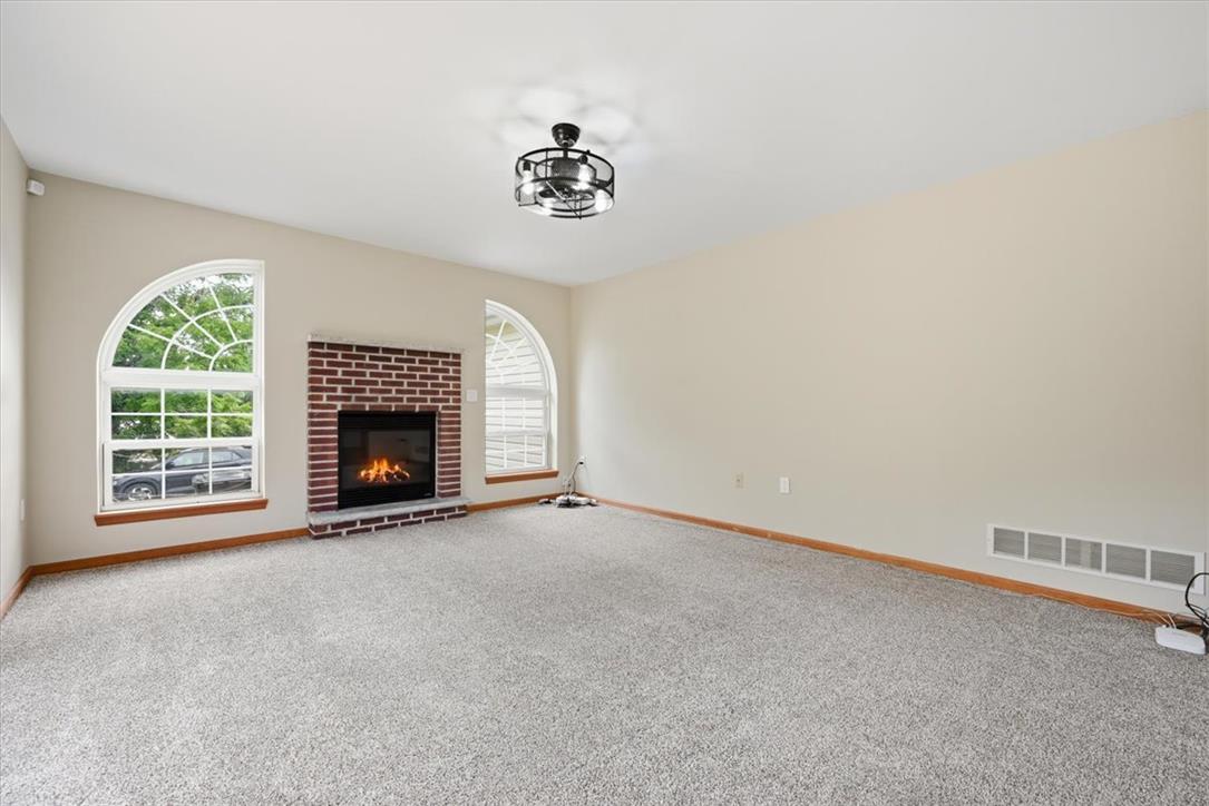 387 Blue Ridge Road Saylorsburg, PA 18353 - Photo 11 of 90 A well-lit living space features a cozy brick fireplace and graceful arched windows.