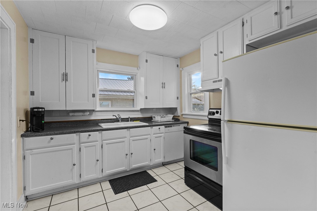 640 Plainfield Road Akron, OH 44312 - Photo 9 of 25 Kitchen featuring white appliances, dark countertops, and white cabinetry