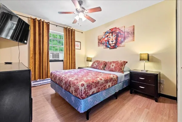 a bedroom with a bed dresser and a large window