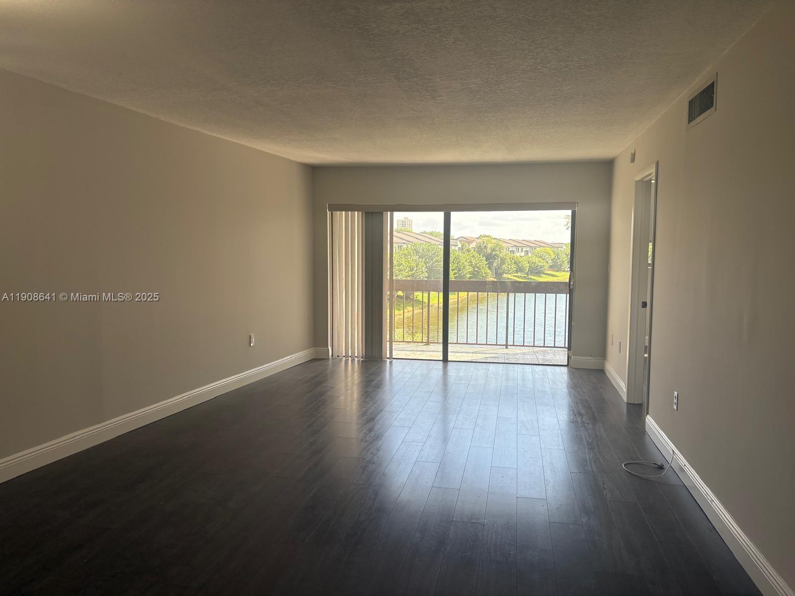 10288 Northwest 9th St Circle, Unit 307 Miami, FL 33172 - Photo 2 of 14 a view of an empty room with wooden floor and a window
