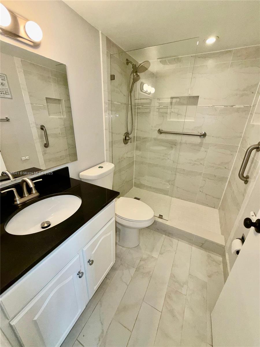 10288 Northwest 9th St Circle, Unit 307 Miami, FL 33172 - Photo 10 of 14 a bathroom with a double vanity sink toilet mirror and shower