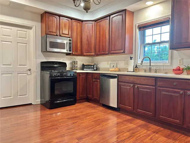 a kitchen with stainless steel appliances granite countertop a stove sink microwave and window