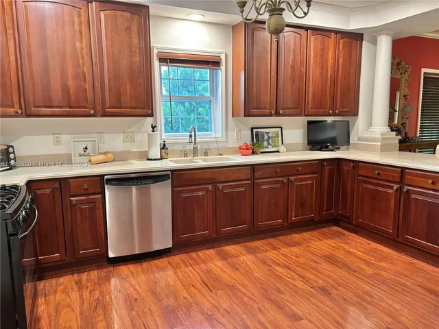 a kitchen with stainless steel appliances granite countertop wooden cabinets a sink and dishwasher with wooden floor
