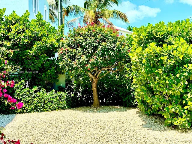 a view of a house with a flower garden and a wooden fence